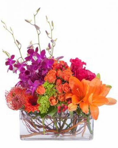 Bright and cheery, this colorful display of premium blooms are artfully arranged in a clear glass container.