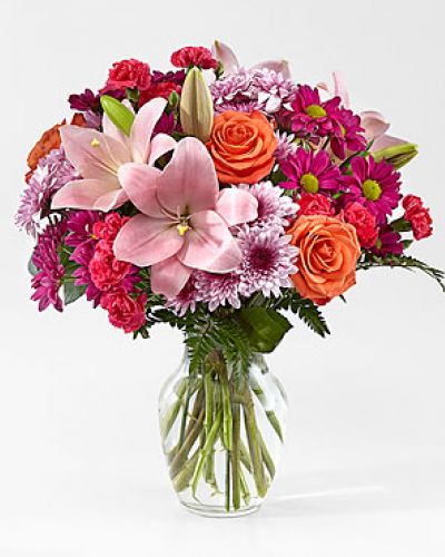 The Light of My Life Bouquet blossoms with brilliant color and a sweet sophistication to create the perfect impression! Pink Lilies make the eyes dance across the unique design of this flower bouquet, surrounded by the blushing colors of orange roses, lavender cushion poms, hot pink carnations, and lush greens. Presented in a clear glass vase, this fresh flower arrangement has been created just for you to help you send your sweetest thank you, happy anniversary, or thinking of you wishes.