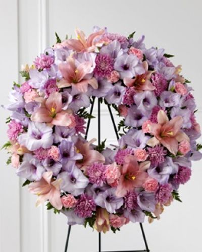 Our Beloved Friend™ Wreath beautifully honors a life that was cherished by so many. This classic arrangement stands tall with an array of lilies, gladiolus and carnations in lavender and pink shades to express your love for the friends who truly feel like family.